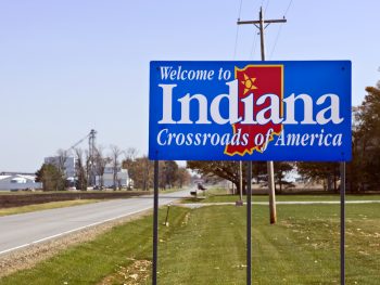 A blue sign welcoming you to Indiana that says 'Crossroads of America'. It is a blue sign with the shape of the state in red with a star over the second i in the word. One of the best things to do in Indiana
