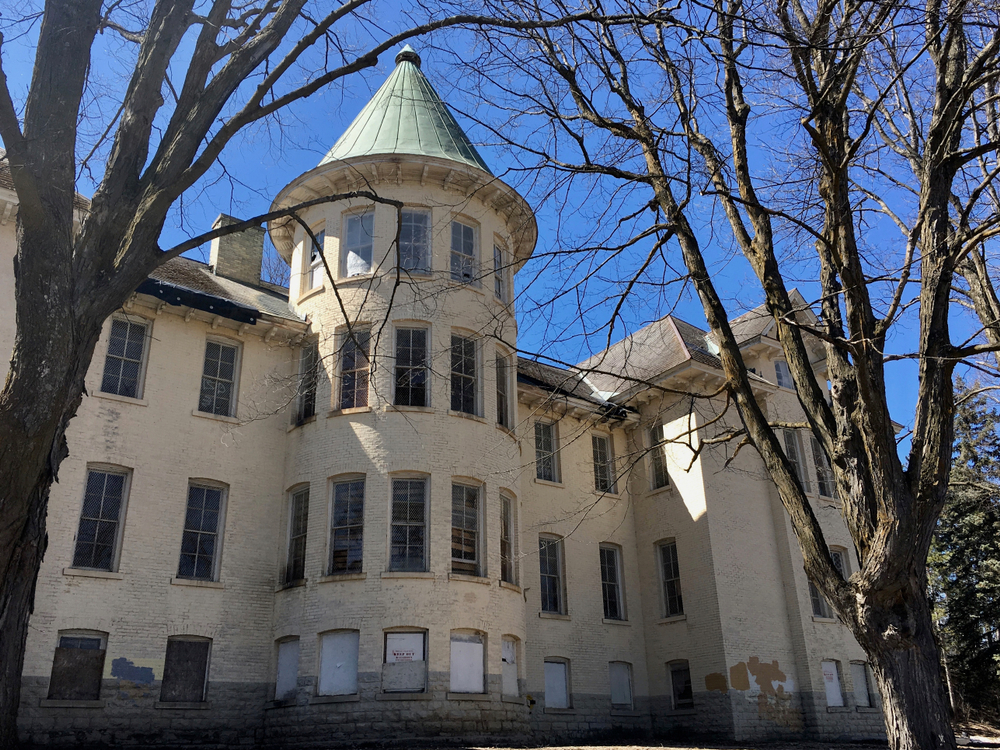 A cream building with a tower and windows The abandoned Historic Traverse City State Hospital one of the things to do in Traverse City