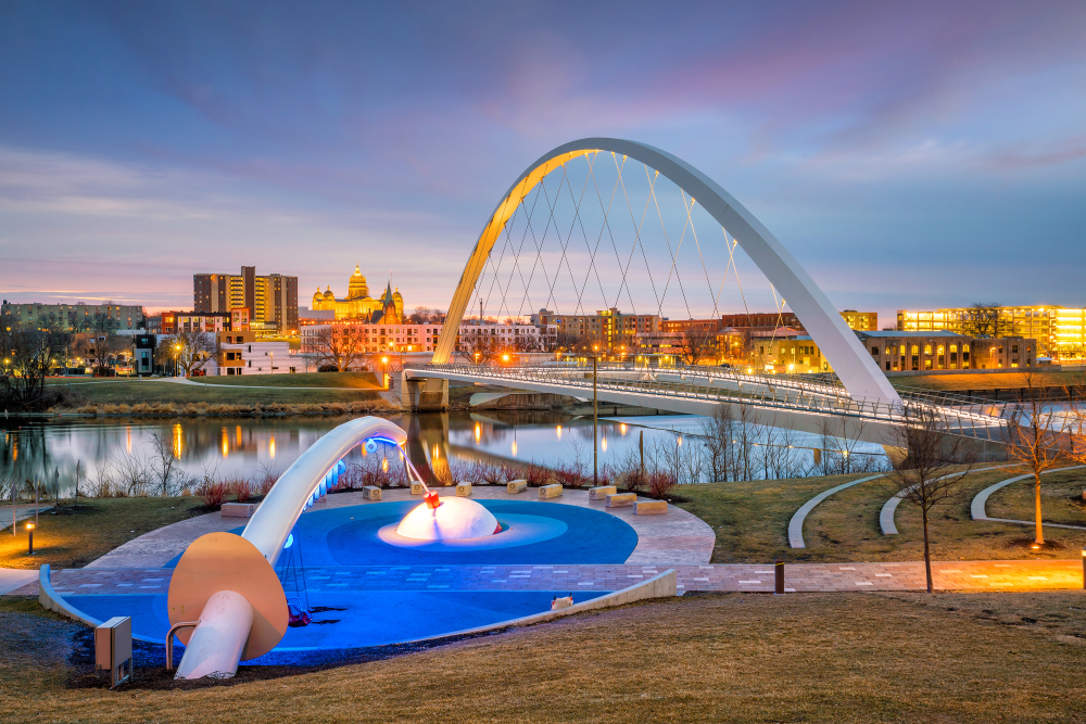 The Des Monies, Iowa, skyline at dusk with a lit up bridge and a park.