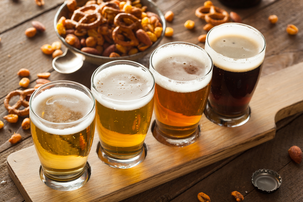 A flight of four different kinds of beer. They are placed from lightest color to darkest color on a wooden paddle. On the table you can see a bowl of peanuts and pretzels. 
Activities in the Wisconsin Dells
