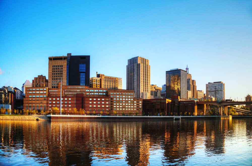 The view of the St. Paul skyline from the river. It is buildings of all different heights. You can just barely see the skyline being reflected in the river. 