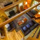 Overhead picture of log cabin living room with brown leather furniture and stone fireplace