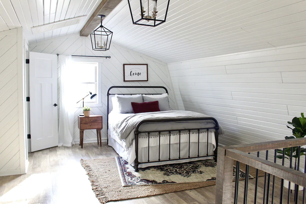 Farmhouse chic bedroom with iron frame, white bedding and ship lad on walls. Beautiful cabin in Ohio.