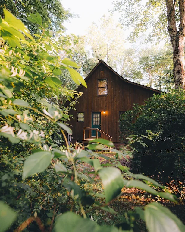Dark wood cabin with black door. surrounded by greenery. Cabins in Ohio