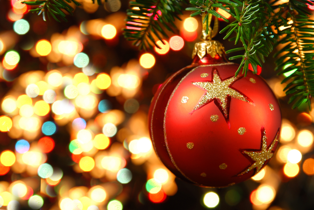 Close-up of a red and gold ornament with pretty lights in the background.