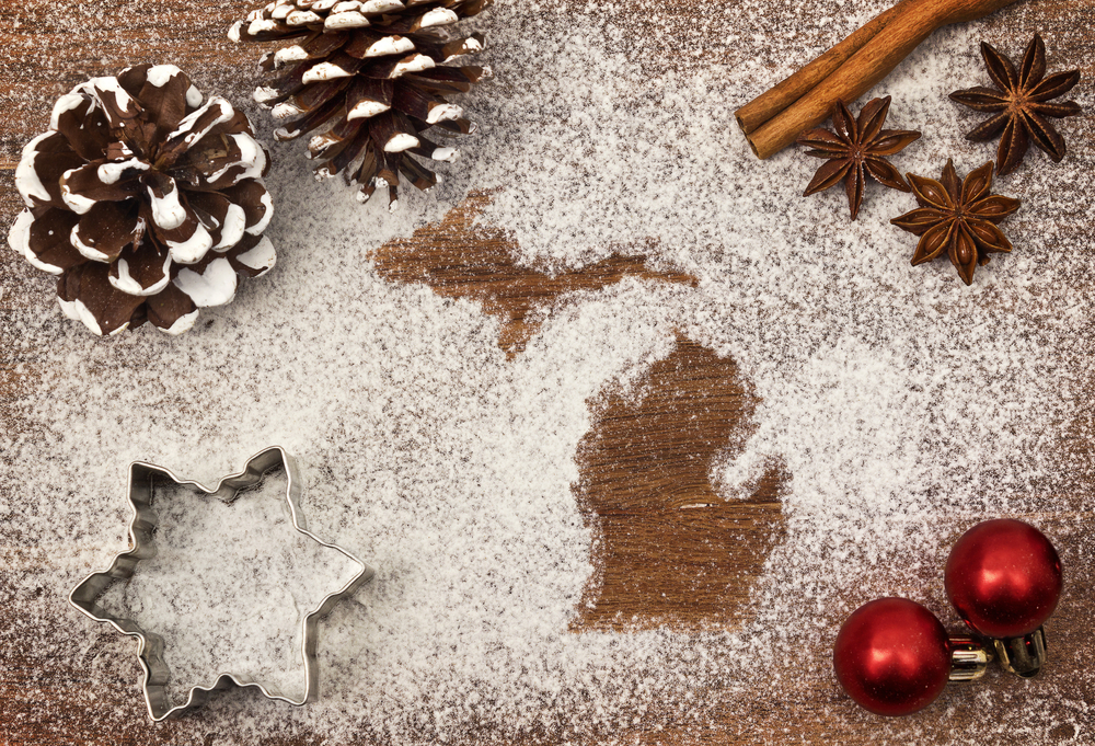 two pinecones, red ornaments, a star cookie cutter surround imprints of state of Michigan in powdered sugar. Christmas in Michigan.