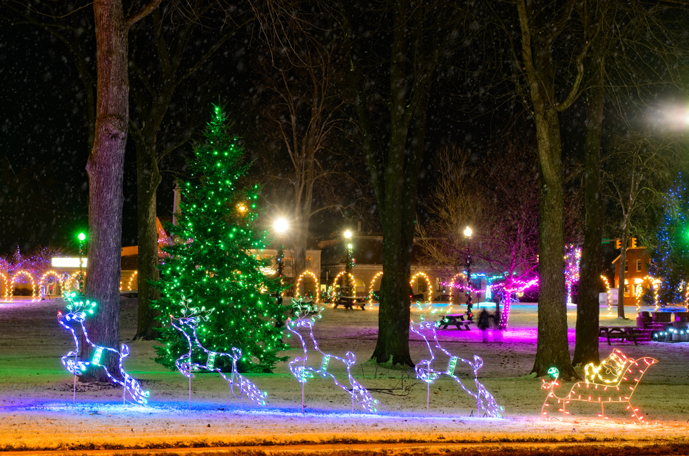 Beautiful Ohio Christmas display  illuminated green lights on evergreen tree, Santa and his reindeers in foreground, snow on the ground.