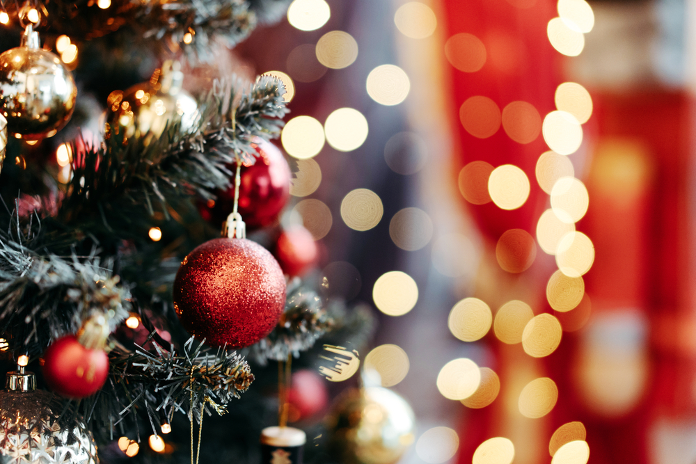 colorful lights in background with green tree in foreground with red ornaments handing to celebrate Christmas in Ohio