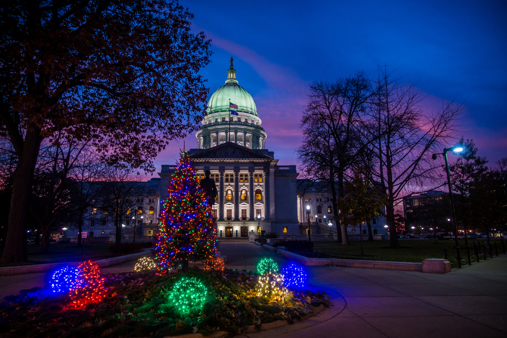 The Wisconsin State Capitol at sunset with a Christmas tree in front.