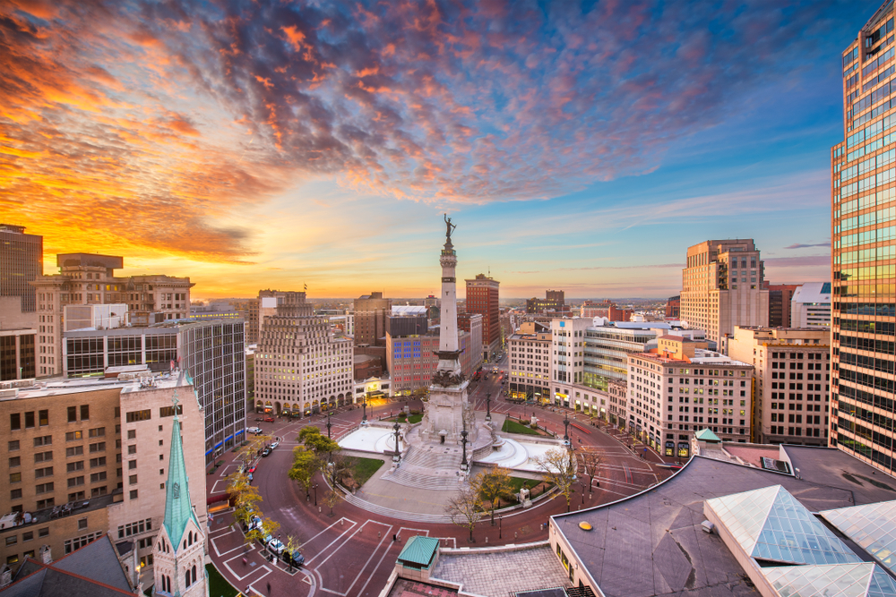 Aerial photo of Monument Circle surrounded by skyscrapers during sunset.