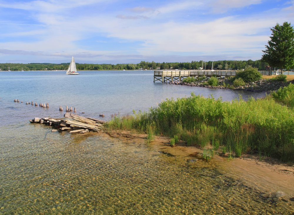 Sailboat with white sail in middle of lake with clear water in foreground and green trees in background.
Romantic getaways  in the Midwest.