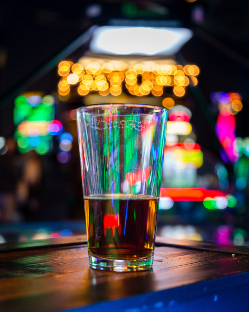 A beer glass in front of arcade lights.