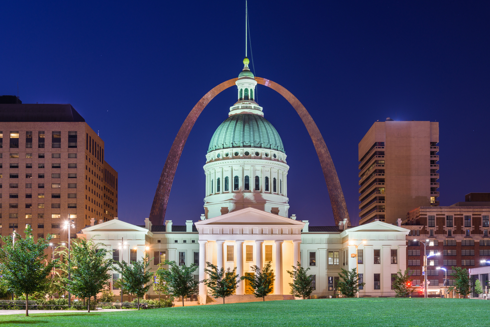 The Old Courthouse lit up at night with the Gateway Arch behind it.