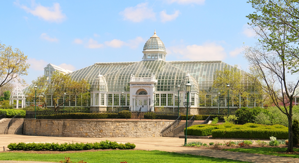 Franklin Conservatory, one of the best things to do in Columbus Ohio, is pictured here.  It is a large white and glass greenhouse with a turret in the center.  