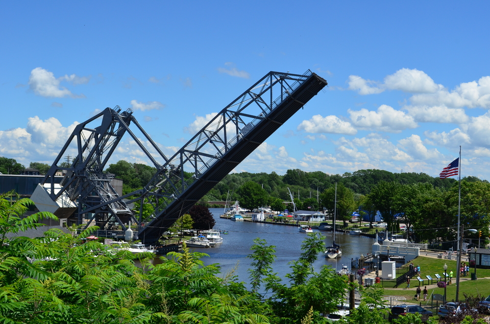 Large iron  bridge lifted up for ships in river below to cross under. Boats in water and blue sky in background. Weekend getaways in Ohio.