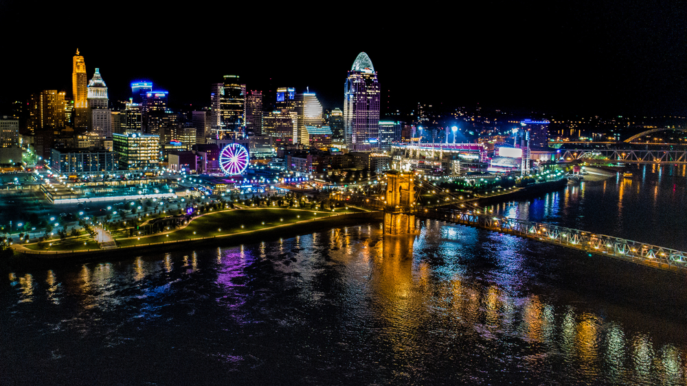 Ohio city at night illuminated with beautiful lights with water in foreground.