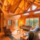 Log cabin interior with A-frame roof, large glass windows.