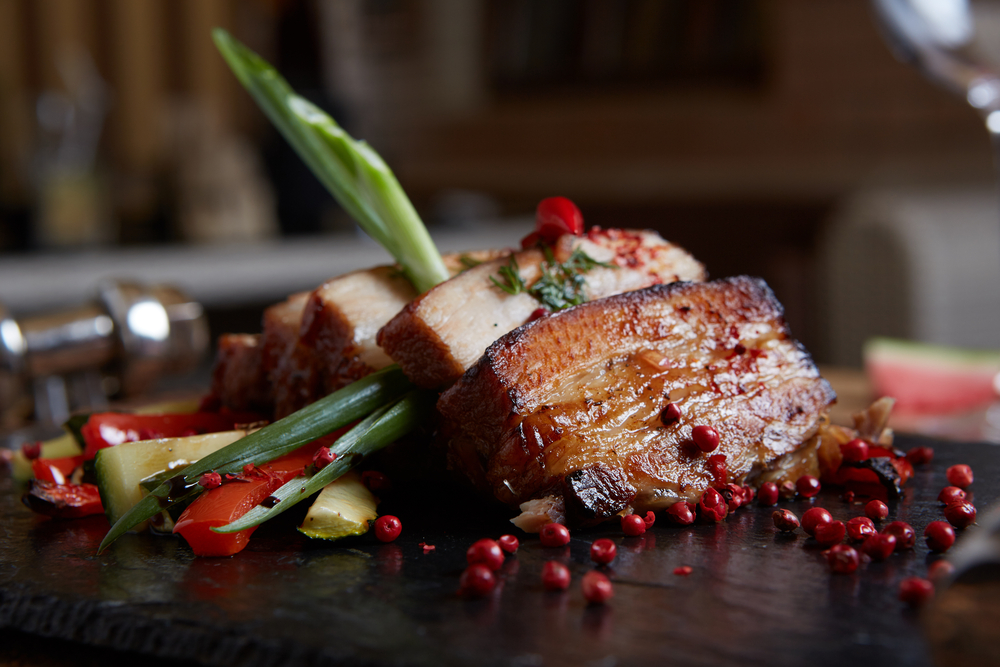 Roasted pork belly on a plate with peppercorns in an article about restaurants in Indianapolis