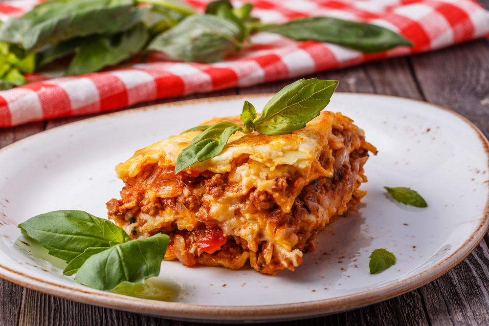 Lasagan on a plate with a red check tablecloth in the background in an article about restaurants in Indianapolis