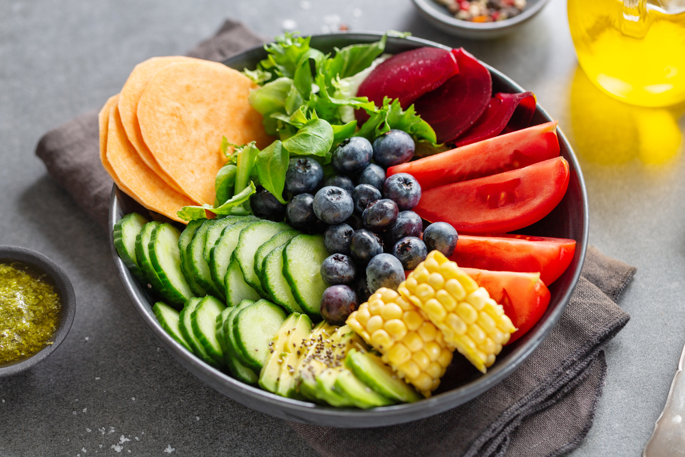 A vegan buddha bow with cucumber, blueberries, tomatoes and corn