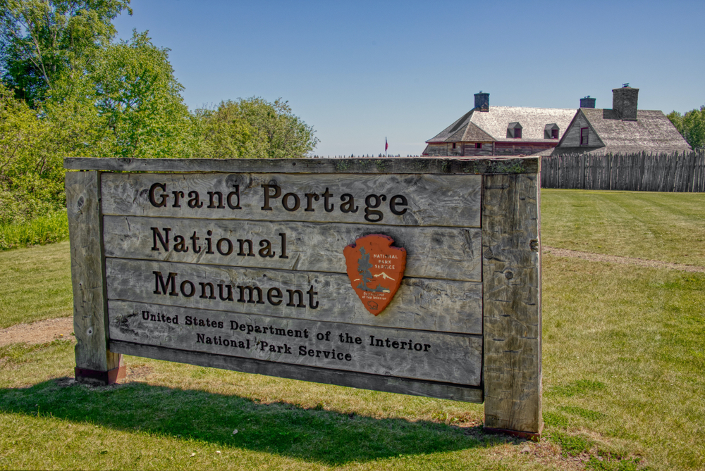Grand Portage National Monument wooden sign with a house in the background