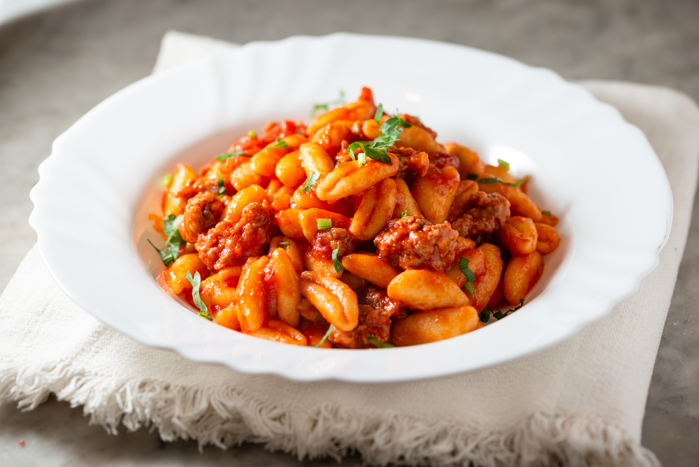 Pasta with red sauce served at one of the restaurants in Des Moines in a white bowl on a white linen napkin.