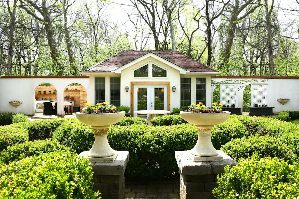 Luxury white villa with manicured lawn and two large white planters in foreground.