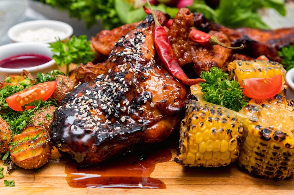 Barbecue Chicken and vegetables on a wooden plate in an article about restaurants in Branson