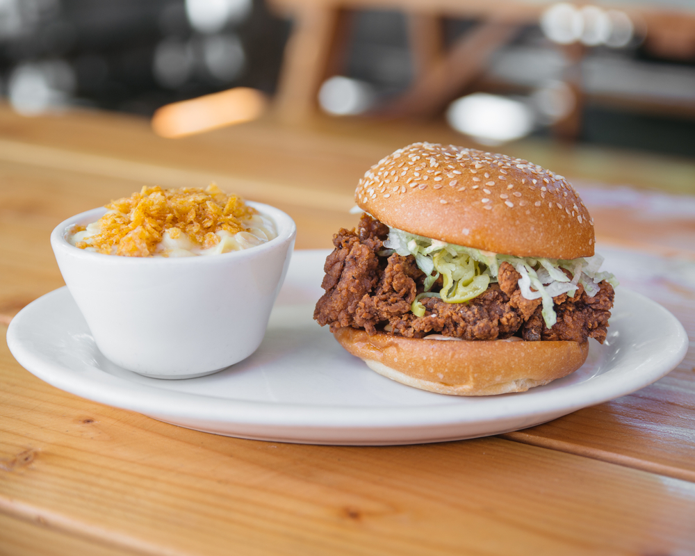 A fried chicken burger in a bun on a white plate