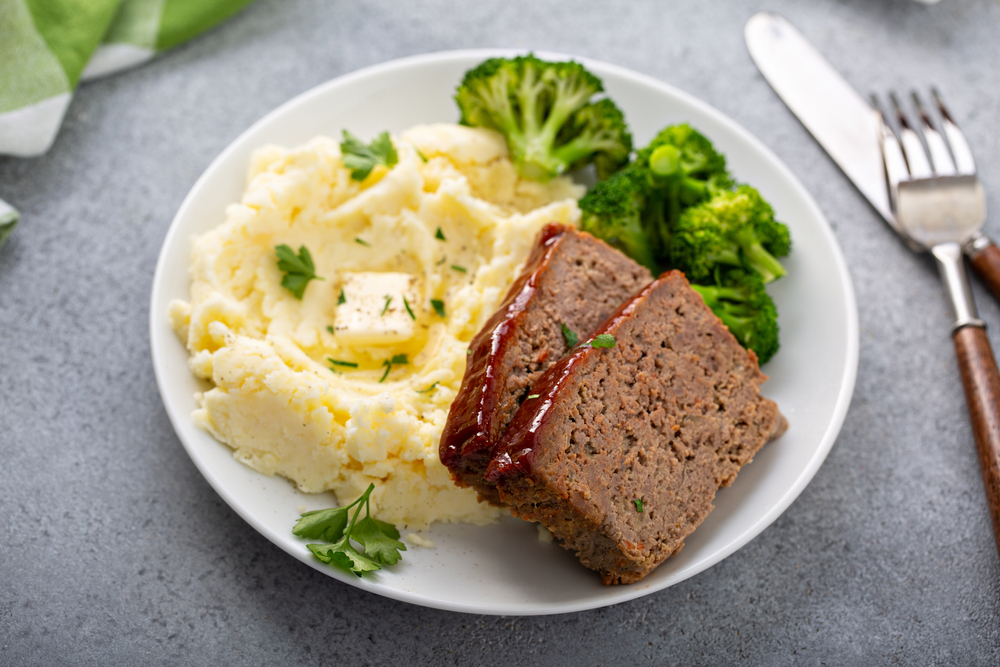 Meatloaf on a plate with broccoli and mashed potatoes