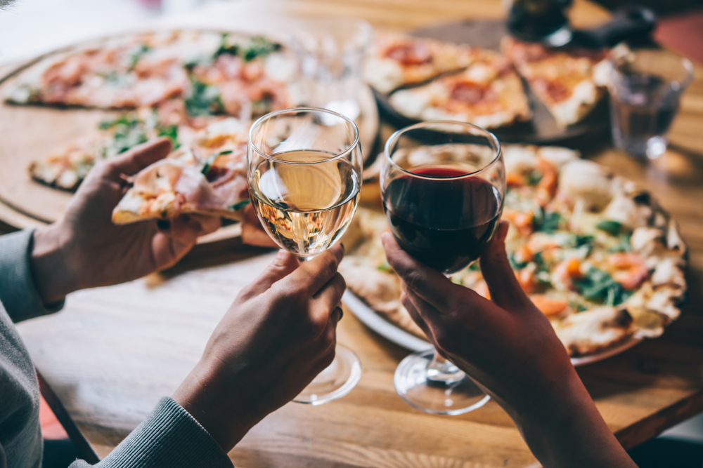 couple enjoying pizza on the table holding up two glasses of wine in an article about restaurants in Branson