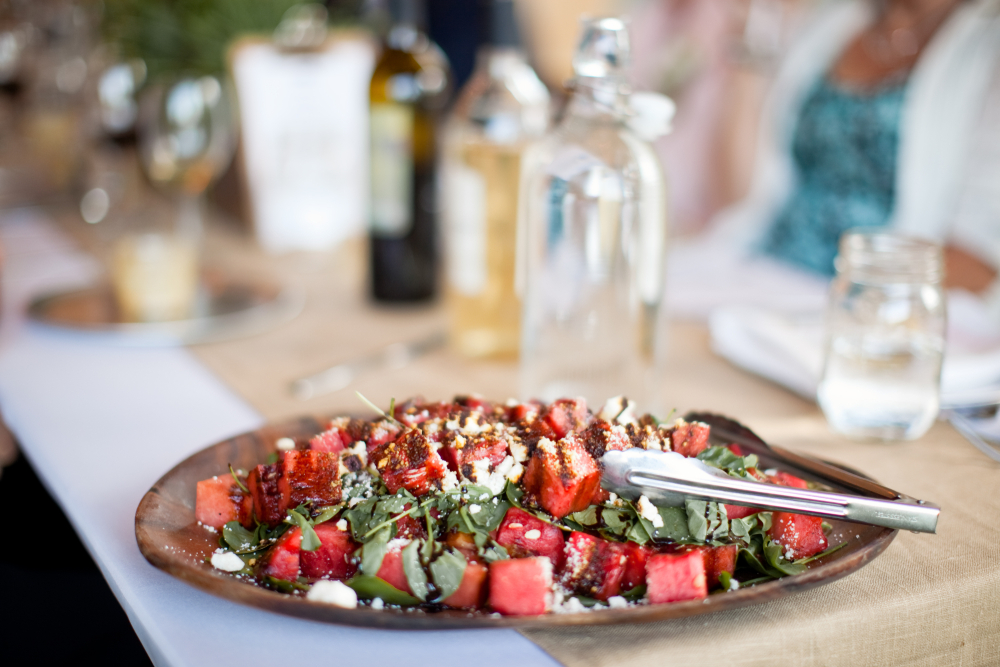 A beautiful looking fresh salad in a plate with wine in the background.