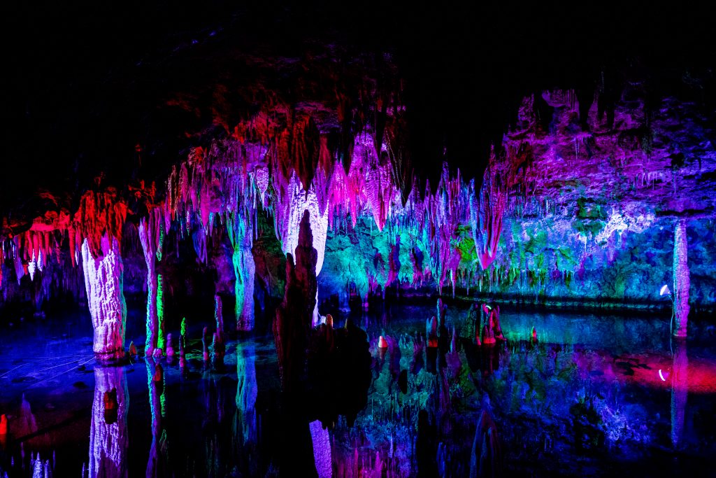 Meramec Caverns lit up with colored lights showing stalactites and water