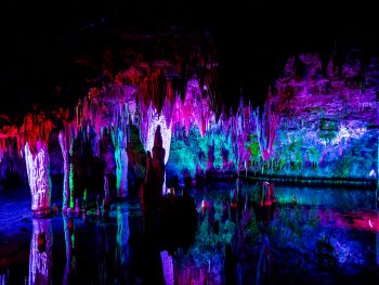 Meramec Caverns lit up with colored lights showing stalactites and water