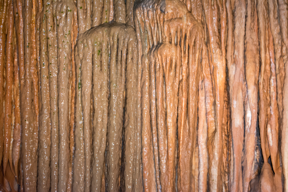 A curtain cave formation in a cave in Missouri displaying brownish vertical rock formations.