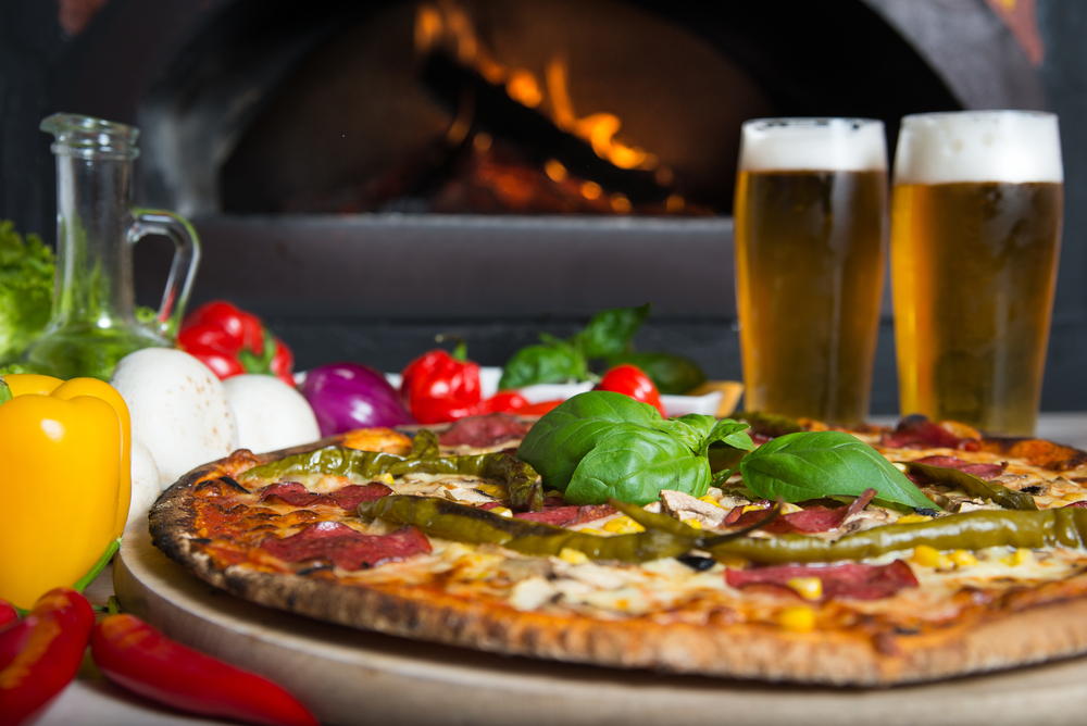 wood-fired pizza with frest veggies and two glasses of beer.