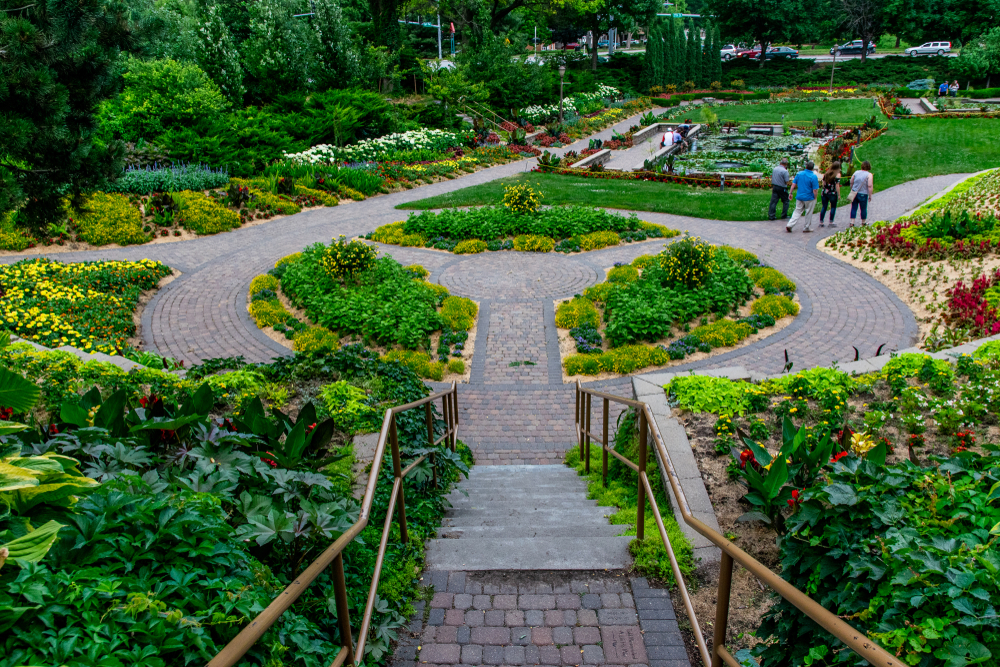 The beautiful Sunken Gardens, one of the best things to do in Lincoln. There are brick pathways, decorative gardens, and you can see people walking through the area.