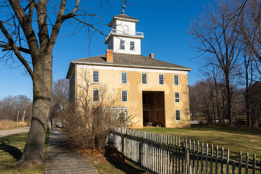 One of the old buildings in Bishop Hill, Illinois is large beige home with tower extending out top of roof with observation deck.