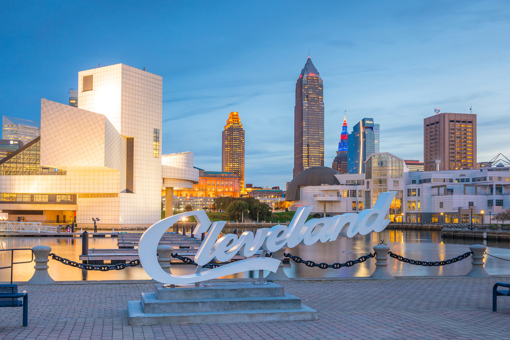 The Cleveland sign in font of the water and city skyline at dusk.