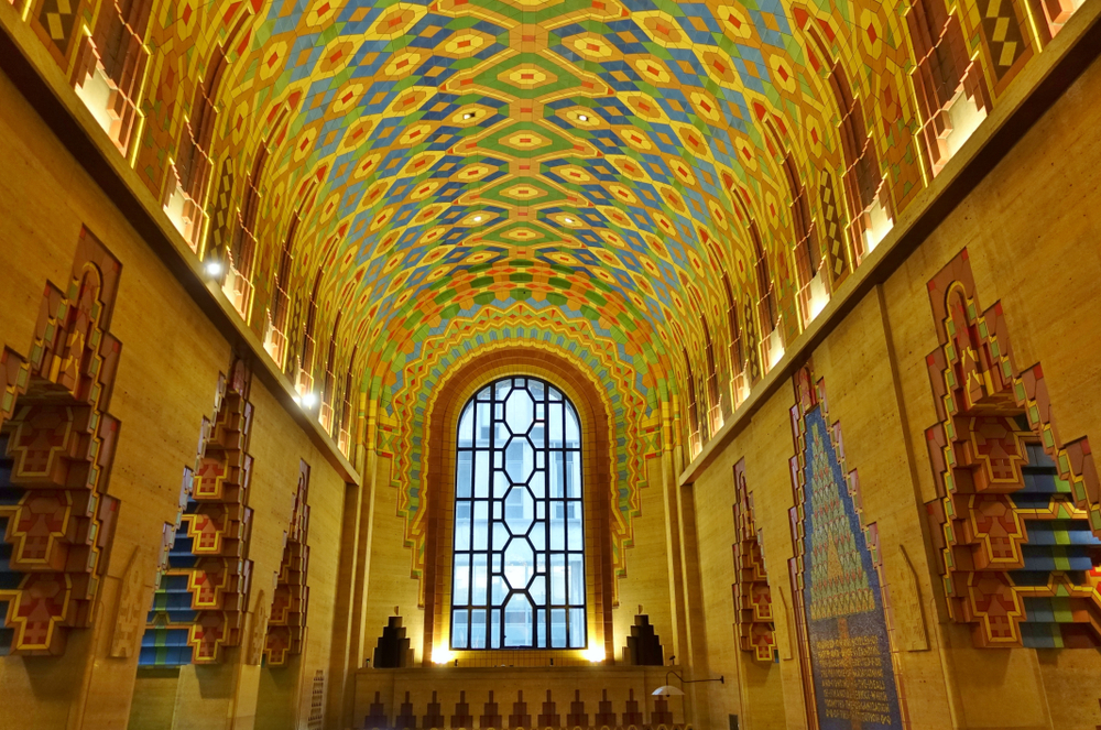 An interior hallway in the Guardian Building in downtown Detroit. It is ornately decorated with Native American, Aztec, and Art Deco designs. It is brightly colored. 