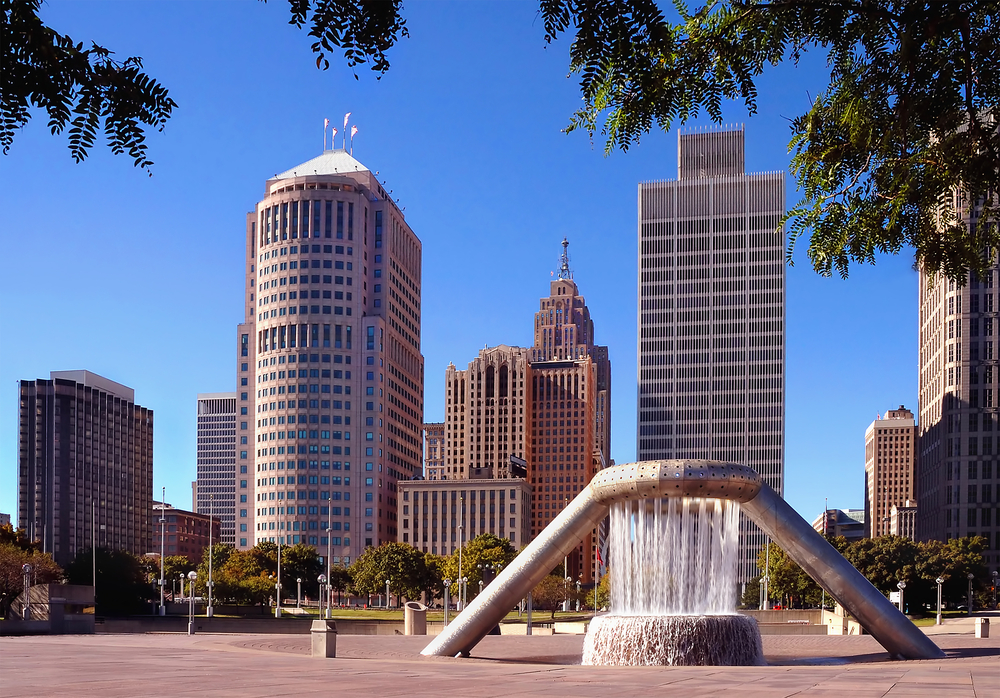 Hart Plaza in the middle of downtown Detroit. There is a large water feature, a paved area, and you can see the city skyline. 