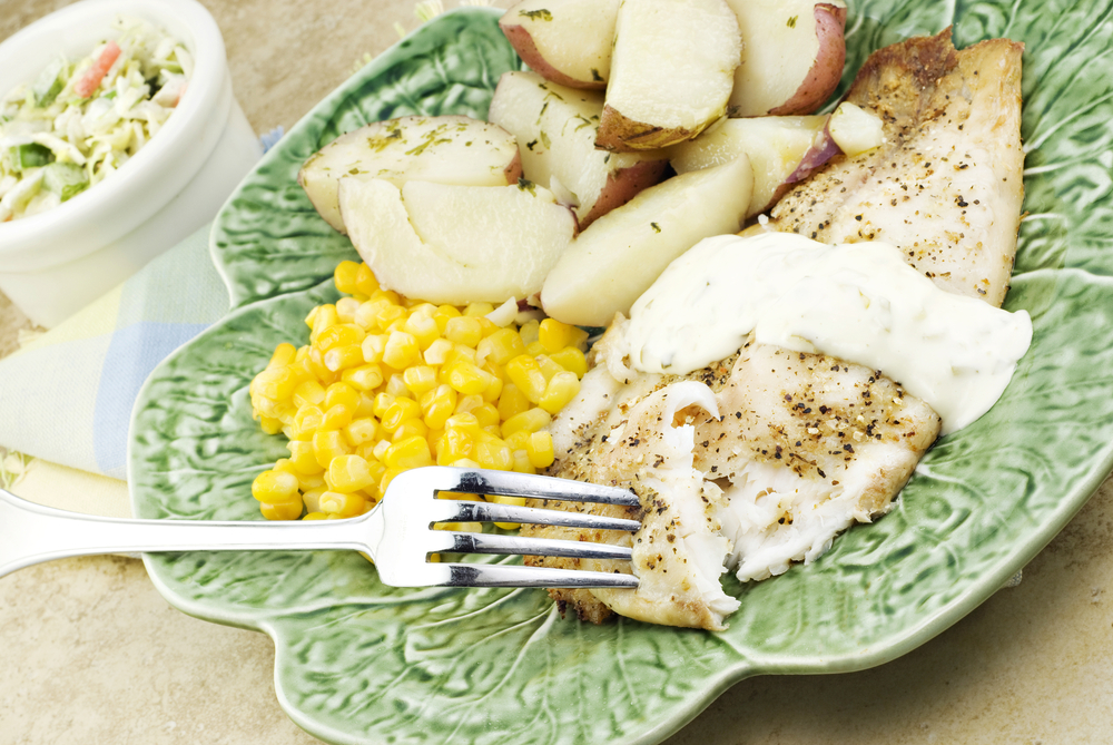 Broiled white fish with potatoes and corn on a plate