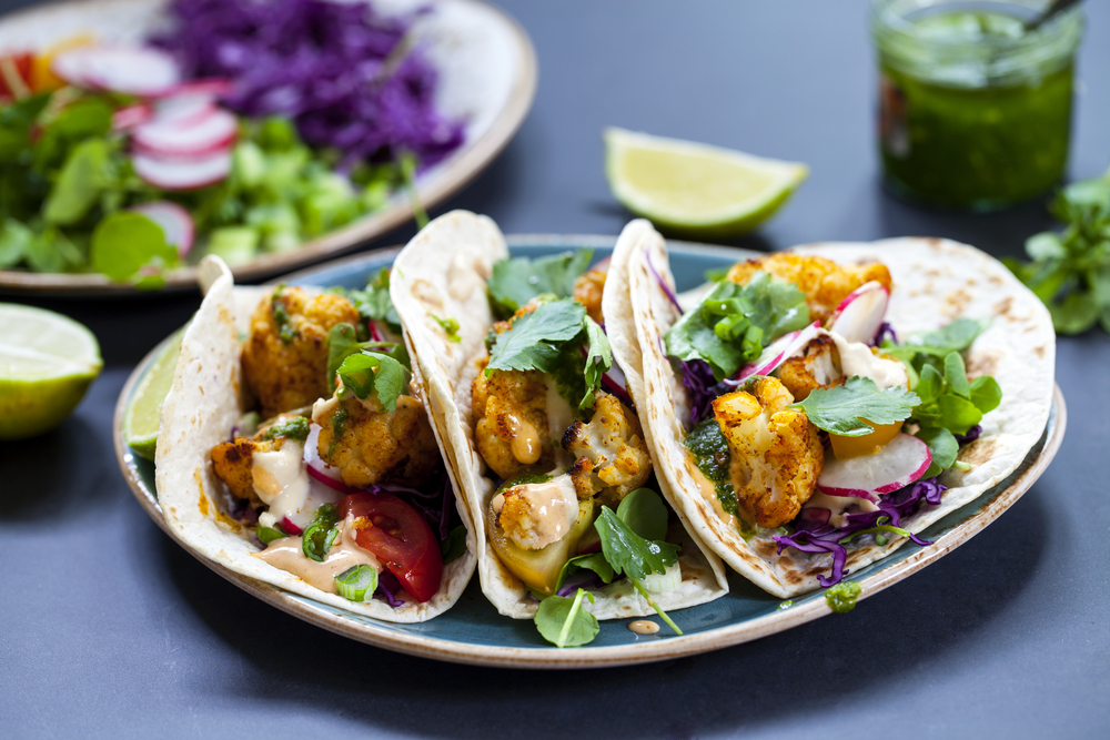 Roast cauliflower and vegetables in taco shells on a plate