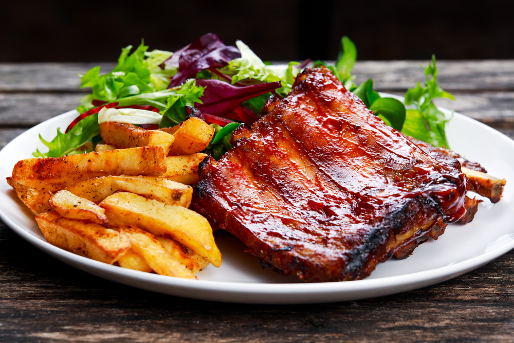 Roasted ribs and fries on a plate with salad.