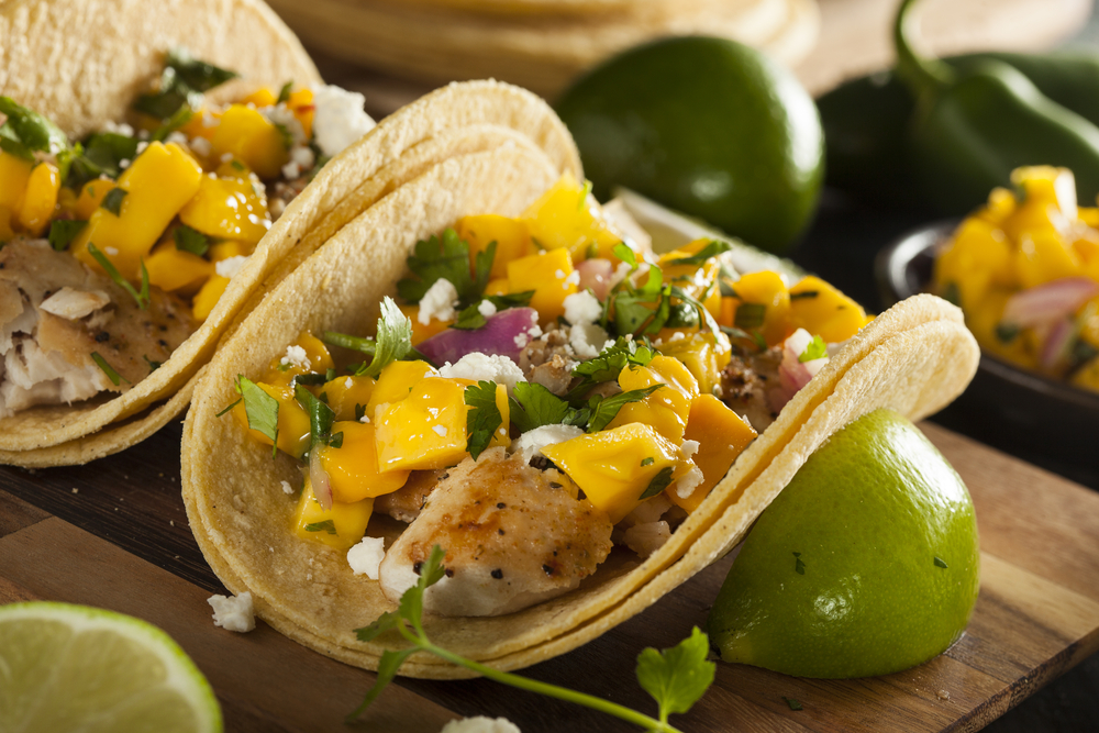 Fish tacos with mango and lime on a wooden board