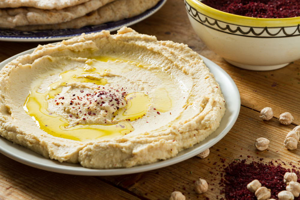 A plate of handmade hummus with oil and paprika on top, served on a wooden table at one of the best restaurants in Kansas City