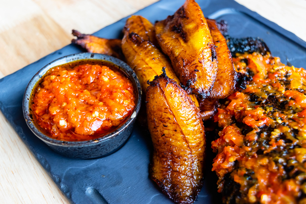 Friend slices of plantain on a plate with a dipping sauce