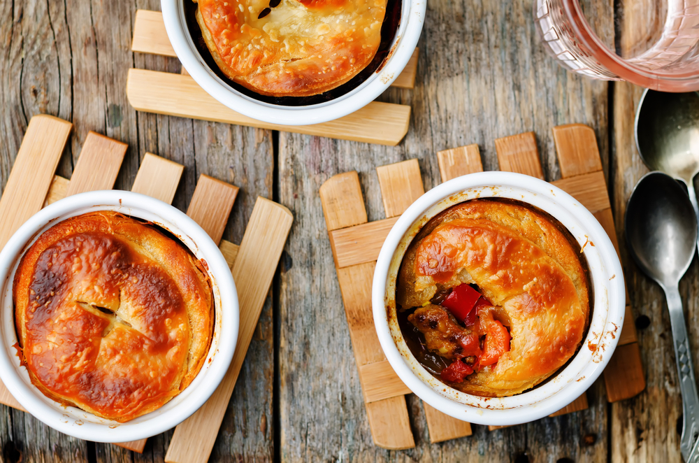 Three pot pies on a table one with a spoonful taken out