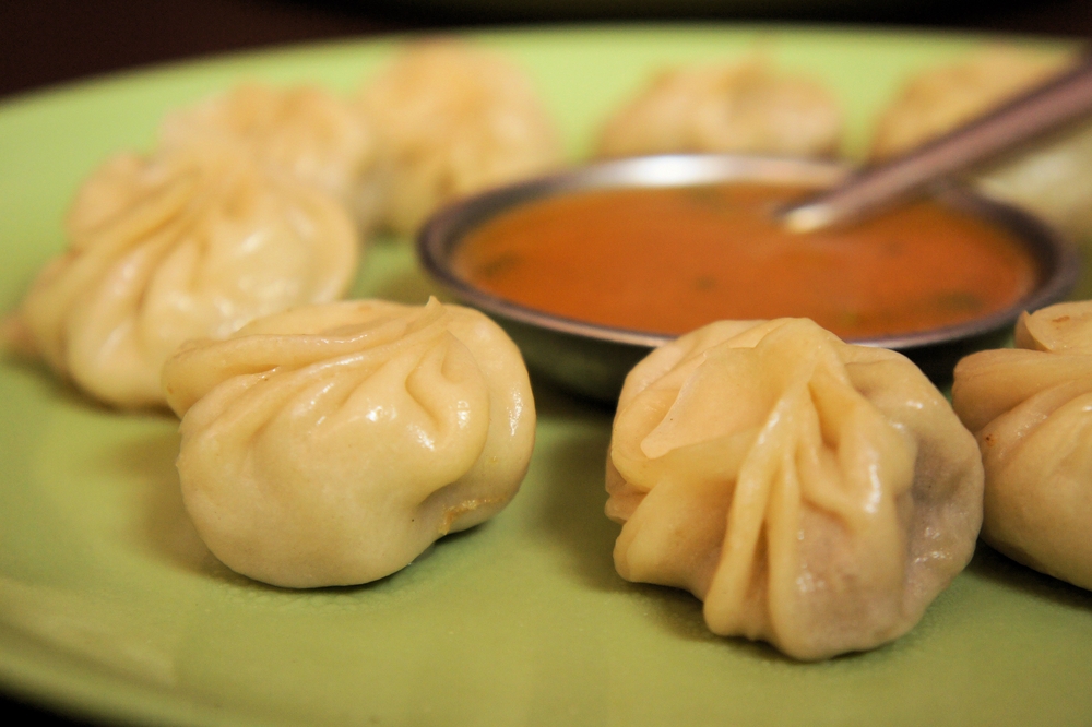 momos placed on a plate around a cup of sauce