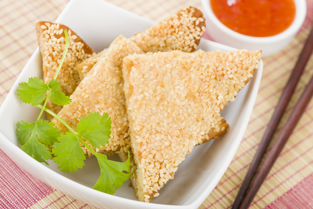 Three sesame prawn toast in a bowl with a side of sause in an article about restaurants in Minneapolis